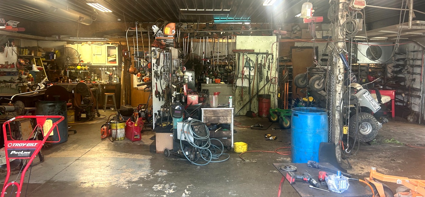Mower up on the lift in the repair bay at M&M Mower Repair